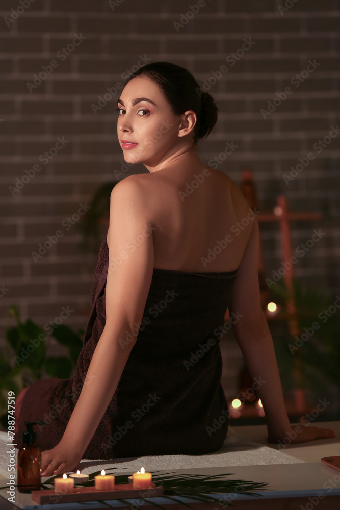 Young woman relaxing in dark spa salon