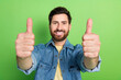 Photo of good mood handsome guy wear denim jacket showing you two thums up empty space isolated green color background