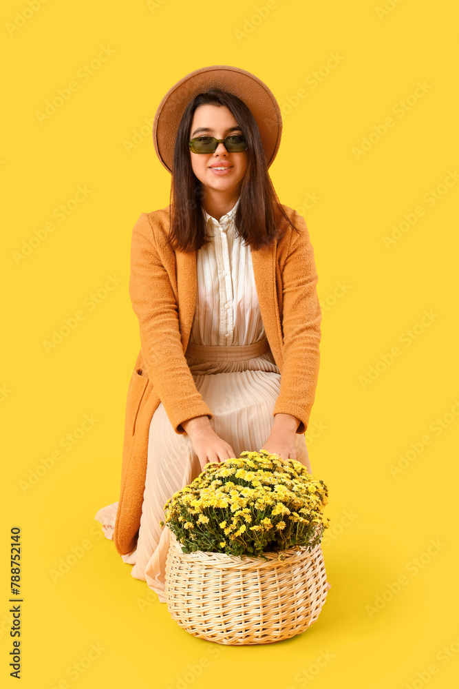 Young woman with chrysanthemum flowers on yellow background
