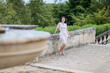 Pretty woman walking near fountain in picturesque old park