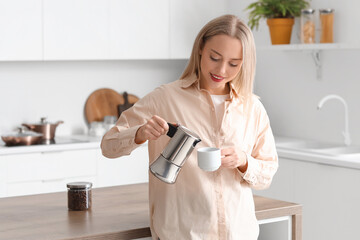 Canvas Print - Pretty young woman pouring espresso from geyser coffee maker into cup in modern kitchen