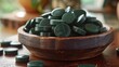 Wooden bowl holds green pills on table, showcasing art with natural materials