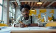 A young african american man creative engineer in glasses works in modern office on drawings of wind turbines. Male architect student working on project