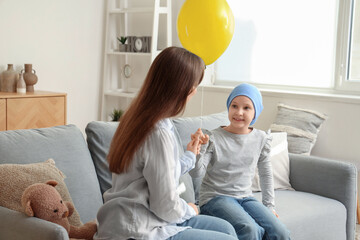 Sticker - Little girl after chemotherapy with blue balloon and her mother at home. International Childhood Cancer Day