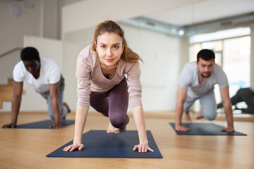 Concentrated sporty young woman doing intense bodyweight workout in fitness studio, performing mountain climber exercise in plank pose..