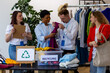 Group of volunteers, young women and man, sorting clothes in charitable foundation for charity donation, recycling. Concept of textile pollution, conscious consumption. Ecology, sustainable lifestyle