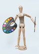 A wooden man holds a palette and a brush in his hand on a white background. Artist and creativity concept.