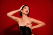 Photo of korean young lady touch breast look empty space dressed black leather garment isolated on red color background