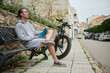© Taras Grebinets - Young hipster sporty man holding a a sports bottle of pure water, sitting on a bench near his electric battery powered motor bike