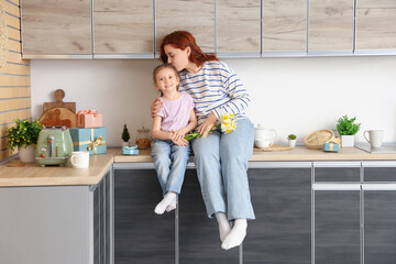 Wall Mural - Little girl and her mother with bouquet of daffodils in kitchen. Mother's Day