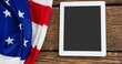 American flag draping next to white tablet on a wooden surface