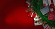 A Christmas wreath and gifts with tags lie on red background