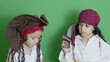 Pirates fight with cutlasses. Cute brothers dressed as pirates playing isolated on green background. High quality photo