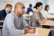 © JackF - Focused adult latin american man listening to lecture in classroom with group. Postgraduate education concept