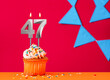 Birthday cupcake with candle number 47 on a red background with blue pennants
