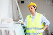 Woman in hardhat and yellow vest counting drywall sheets