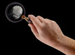 Male Hand Holding Magnifying Glass Viewing A Fingerprint on a Black Background.