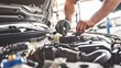 Auto mechanic inspecting a car engine under the hood in a car repair shop