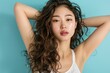 Young Asian beauty woman curly long hair with korean makeup style on face and perfect clean skin show armpits on isolated blue background. Facial treatment - generative ai