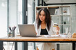 © Satori Studio - Businesswoman at a desk with a laptop, holding a credit card and looking intently at the screen.