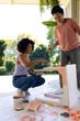 Biracial mother and adult daughter painting furniture outdoors at home in an upcycling project