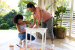 Biracial mother and adult daughter painting furniture outside at home in an upcycling project