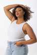 Biracial young female plus size model with curly brown hair posing confidently on white background, 