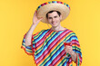 © New Africa - Young man in Mexican sombrero hat and poncho with cocktail on yellow background