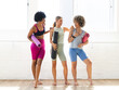 © Wavebreak Media - Three diverse women are chatting in a bright yoga studio, holding mats, copy space