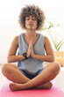 © Wavebreak Media - Biracial young female practicing yoga in studio, sitting on pink mat