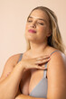 © Wavebreak Media - Caucasian young female plus size model with closed eyes, touching shoulder, on beige background