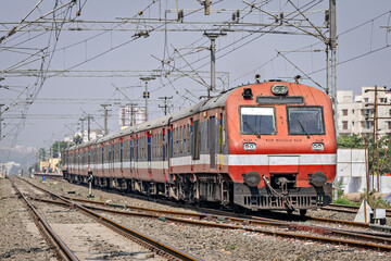 Indian Railways Diesel-Electric Multiple Unit local train exiting out of a wayside station near Pune