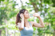 Young fitness woman wearing sports clothes drinking fresh water, Beautiful Asian girl in sportswear drinking water from a bottle