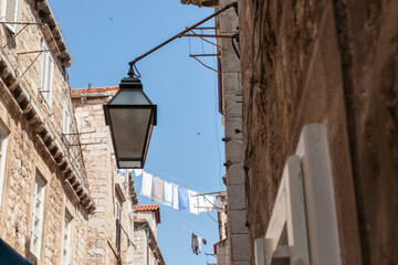 Canvas Print - Laundry hanging high above the street between two old stone apartment buildings in European city