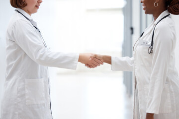 Female doctor and nurse, shaking hands for partnership, agreement and thank you for assistance. Happy, healthcare workers and handshake for teamwork, trust and support together in hospital or lab