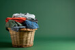 A laundry basket full of t-shirts, pants, shirts, jeans, with a dark green background