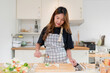 Young asian woman using tongs to cooking delicious sandwich and fresh vegetables salad for healthy breakfast food to preparing homemade snack in modern kitchen with healthy lifestyle at home