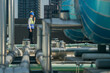 A professional engineer communicates via walkie-talkie on a building's rooftop, surrounded by piping and ductwork.
