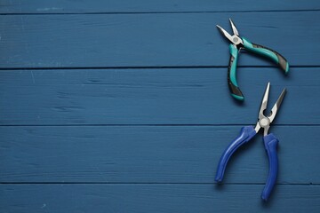 Canvas Print - Pliers on blue wooden table, flat lay. Space for text