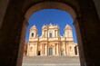 Basilica Minore di San Nicolo (Cathedral of St Nicholas), located on Piazza del Duomo (Duomo Square) in Noto, Syracuse, Sicily, Italy, viewed through the arcades of the town hall (Ducezio Palace)