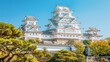 A picturesque view of Himeji Castle, one of Japan's most iconic landmarks and a UNESCO World Heritage Site, with its elegant white walls and graceful architecture standing against a clear blue sky.