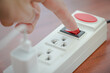Close-up of electrician's hand using red push button to turn on the power strip,Save electricity by turning off the human finger on the red button on the electrical plug.