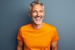 Portrait of a grinning man in his 50s donning a trendy cropped top isolated on solid color backdrop