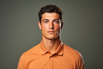 Portrait of a glad man in his 20s wearing a breathable golf polo in front of solid color backdrop