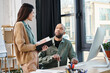 © Bliss - A man with myasthenia gravis and woman discuss a project in an office, standing in front of a computer screen.