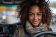 An attractive woman with curly hair is behind the wheel, focused on the road, driving through an urban setting