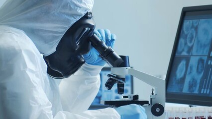 Wall Mural - Scientist in protection suit and masks working in research lab using laboratory equipment: microscopes, test tubes. Medicine, healthcare and technology concept.