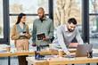 © Bliss - Two men and a woman collaborating on a project, deeply engaged with a laptop in a modern office setting.