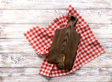 Fototapeta Tulipany - Cutting chopping brown wooden board decorated with red picnic checkered cloth top view. Empty timber,plank. Dish plate advertisement design.