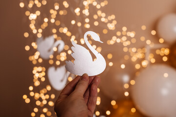 A close-up of a paper swan decoration illuminated by warm lights, ideal for craft or event design concepts.